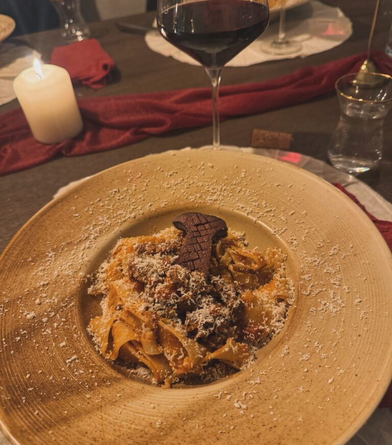 Een bord met Pappardelle met wildzwijn op een chique opgemaakte tafel